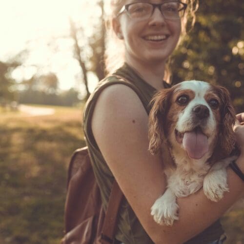 Woman smiling and holding a white and brown dog in her arms.